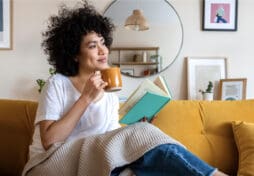 A woman enjoys coffee and a book in her new home.