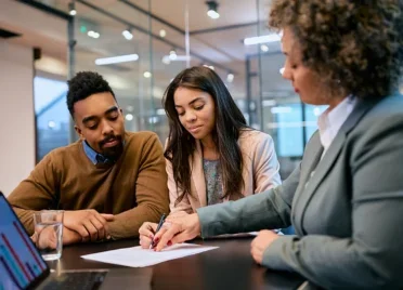 Young black couple signing a loan document with banker in an office.