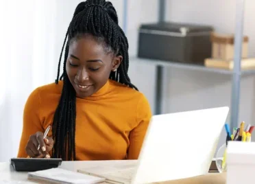 A woman uses a calculator and her laptop to figure out how to get her credit score to 800.