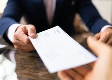 A banker hands a customer a cashier’s check.