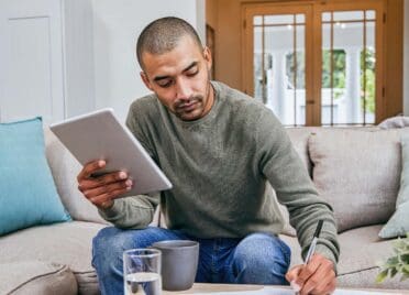 A man in his living room looking over his personal finances.